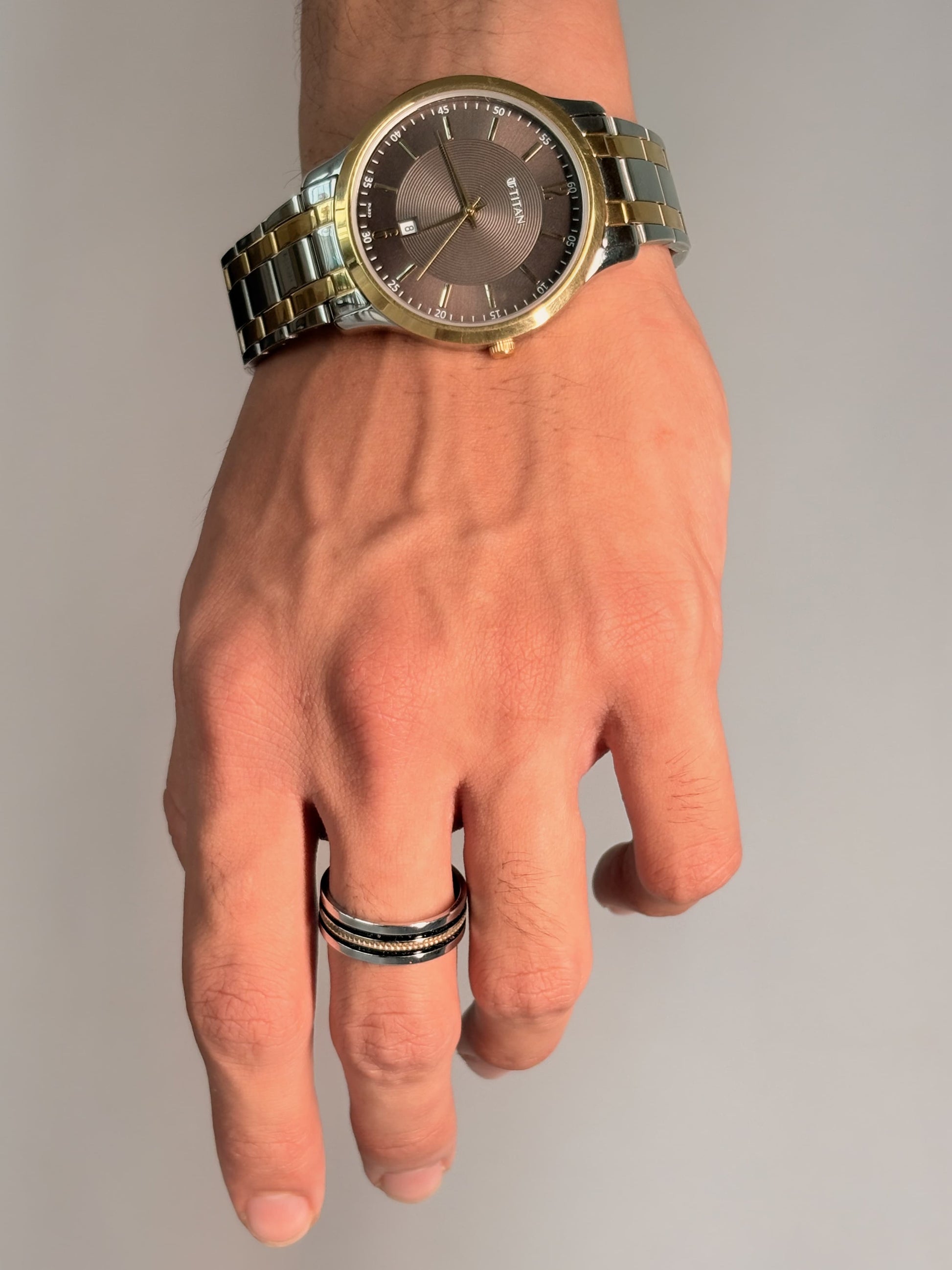 The ring features a central braided gold inlay, adding contrast and elegance to its sleek, masculine design.